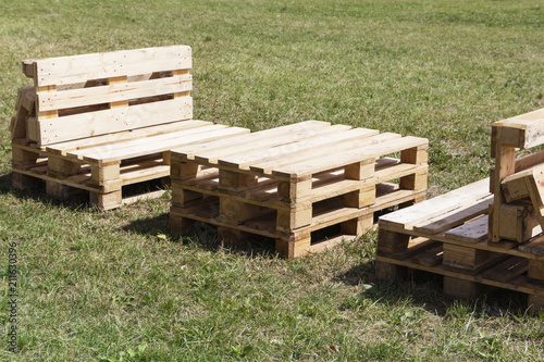 Wooden furniture made of pallets standing on the grass. Chair, table.