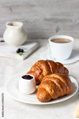 Delicious breakfast with fresh croissants and berries with cup of coffee on a light grey background