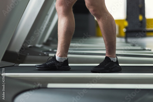Closeup of fitness man legs walking on treadmill at gym