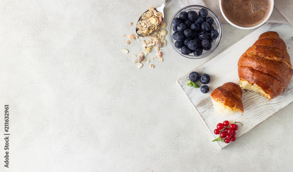 Croissant with fresh berries, muesli and a cup of coffee or hot chocolate on a light background. Copy space Croissant with fresh berries, muesli and a cup of coffee or hot chocolate on a light background. Copy space