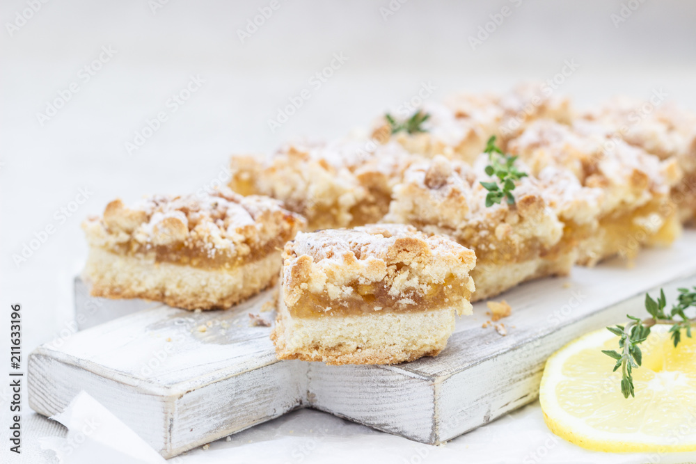 Lemon crumble cake slices or bars on white wooden cutting board, selective focus. Jam bars snack food