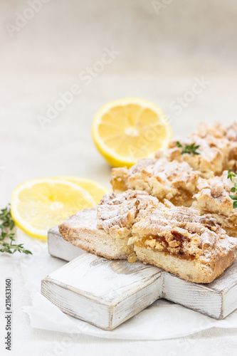Lemon crumble cake slices or bars on white wooden cutting board, selective focus. Jam bars snack food