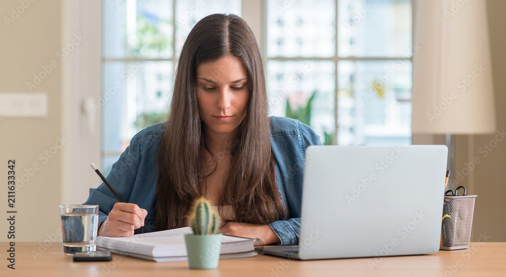 Young student woman studying at home with a confident expression on smart face thinking serious