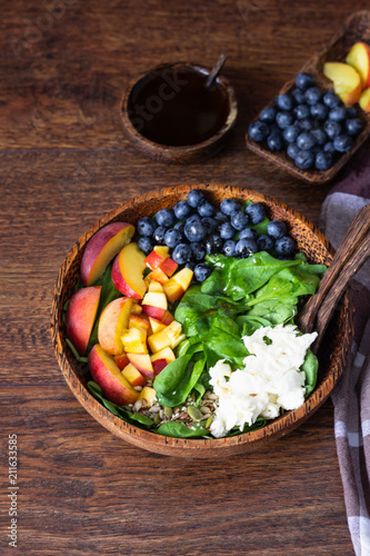 Summer spinach and fruit salad with seeds, mozzarella and balsamic vinegar in a bowl. Summer food concept
