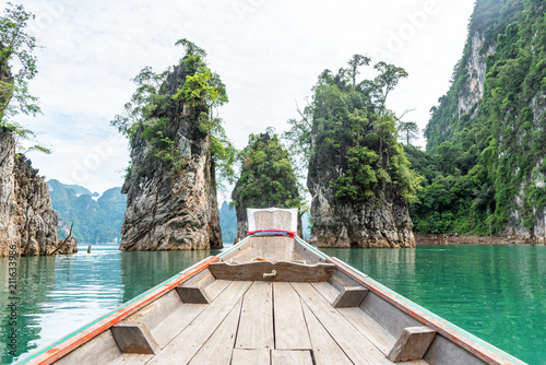 Wooden long-tail boat with rock mountain and lake in Ratchaprapa dam, Khoa Sok National Park, Surat Thani, Thailand. © chanwitohm