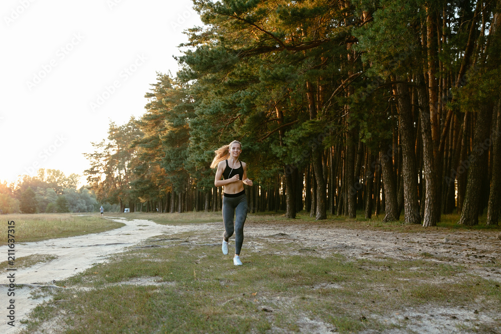 Fototapeta premium Full length photo of cheerful sporty woman jogging outdoors. Dressed up in sportswear. Fitness concept.