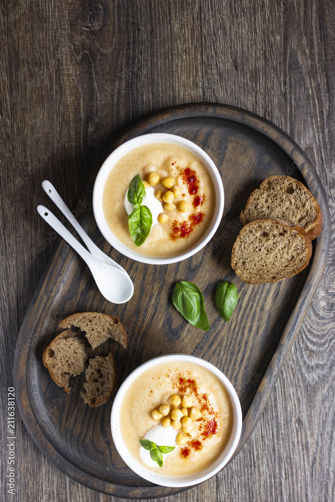 Cream soup with cauliflower, chickpea and sour cream on a dark wood background, top view. Healthy food concept Cream soup with cauliflower, chickpea and sour cream on a dark wood background, top view. Healthy food concept