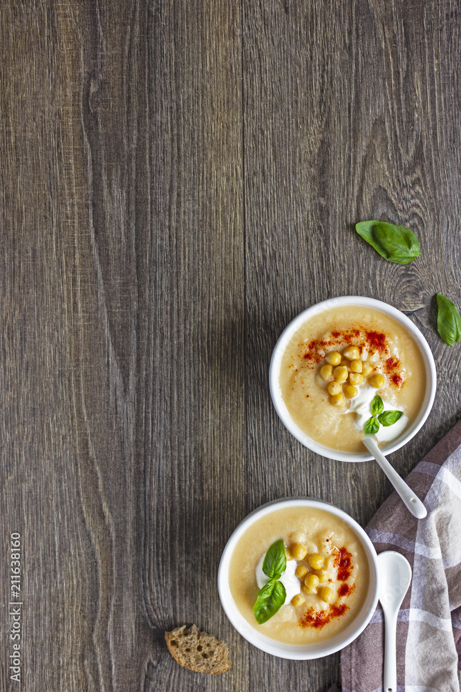Cream soup with cauliflower, chickpea and sour cream on a dark wood background, top view. Healthy food concept Cream soup with cauliflower, chickpea and sour cream on a dark wood background, top view. Healthy food concept
