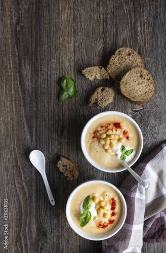 Cream soup with cauliflower, chickpea and sour cream on a dark wood background, top view. Healthy food concept 