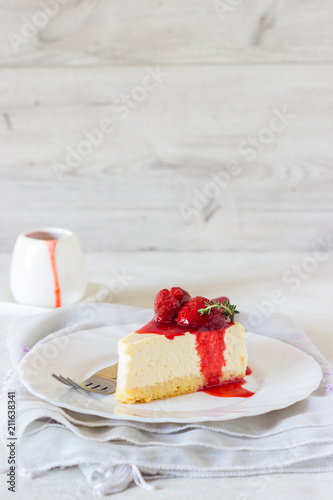 Piece of delicate cheesecake with strawberries sauce on a white plate. 