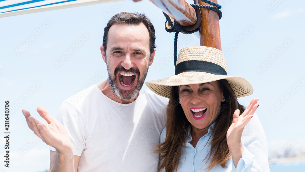 Middle age couple traveling on sailboat very happy and excited, winner expression celebrating victory screaming with big smile and raised hands