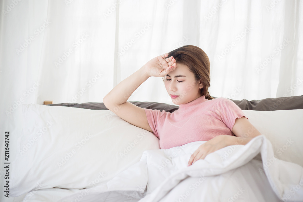 Young asian woman  touching her forehead on the bed. Woman sick concepts : headache, dizziness, fever.