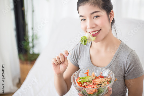 Enjoyed Asian woman eating vegetable salad.