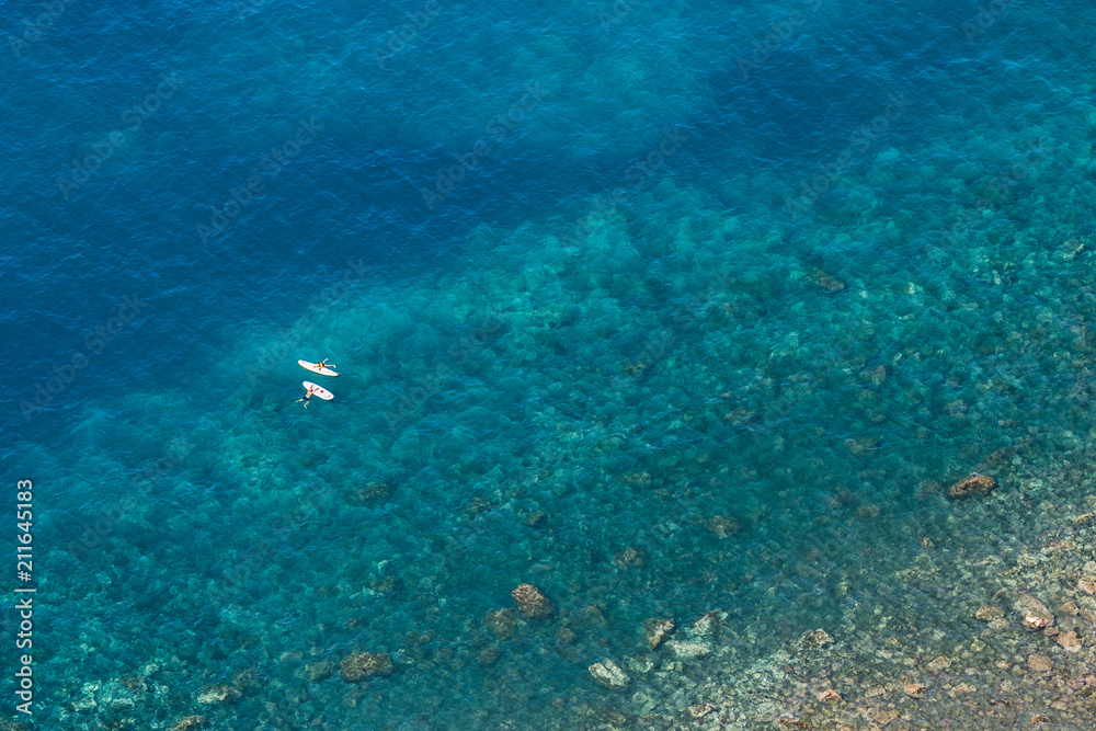 Aerial view of people paddling on tropical water.