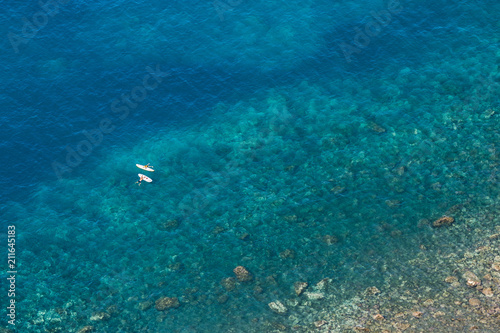 Aerial view of people paddling on tropical water.