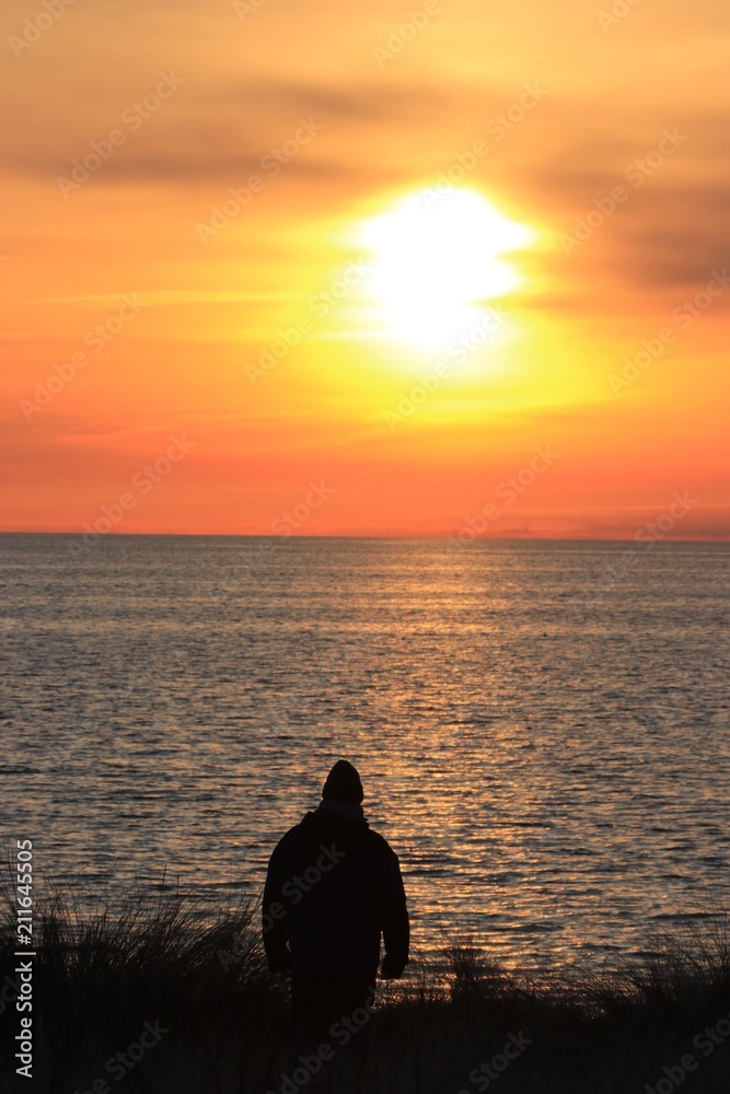 einsamer Mann blickt aufs Meer bei Sonnenuntergang