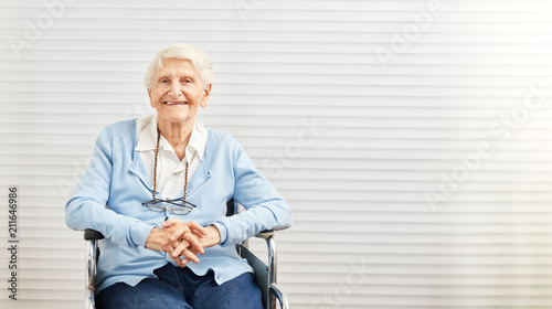 Alte Frau sitzt lächelnd im Rollstuhl im Seniorenheim
