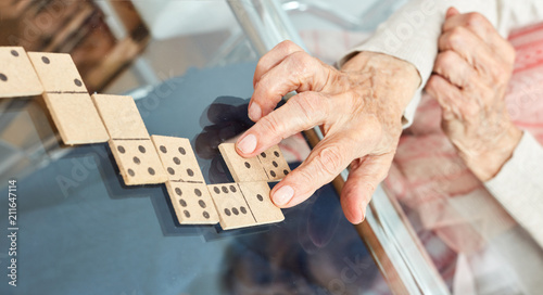 Hände von Senioren legen Spielsteine beim Domino