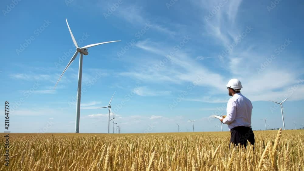 Worker of a wind power plant in a yellow wheat field Worker of a wind power plant in a yellow wheat field