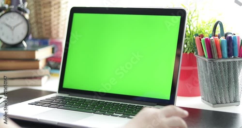 Over the shoulder view of  young boy watching on laptop computer . Green screen of technology being used. Chroma Key laptop. Dolly move left to right.
