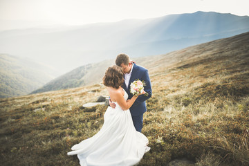 Happy beautiful wedding couple bride and groom at wedding day outdoors on the mountains rock. Happy marriage couple outdoors on nature, soft sunny lights
