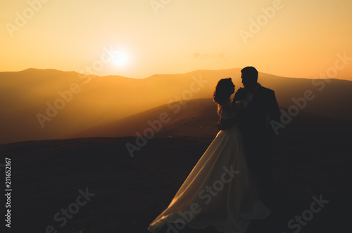 Wedding couple posing on sunset at wedding day. Bride and groom in love