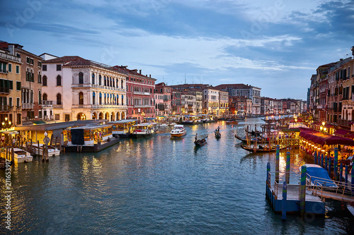Canal Grande with boats and lights in Venice at Sunset. Next to famous Rialto Bridge and the Street  Riva del fin  - Italy