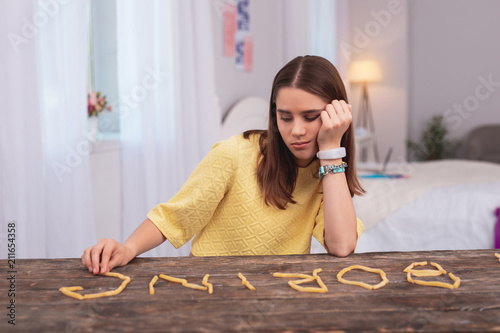Teen life. Sad teen girl touching French fries and leaning on palm