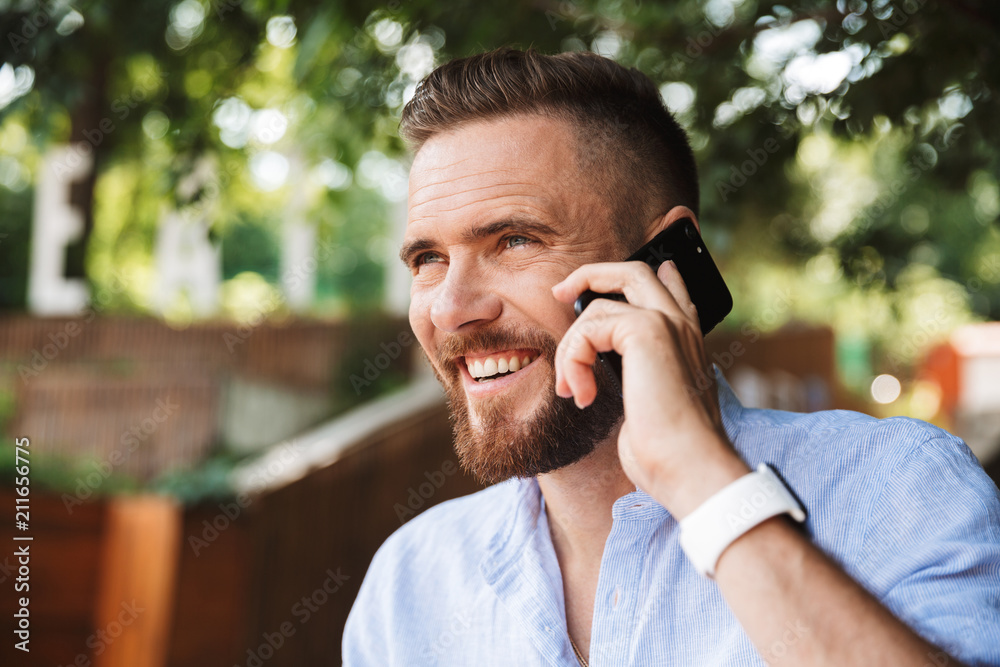 Handsome happy young bearded man talking by mobile phone. Handsome happy young bearded man talking by mobile phone.