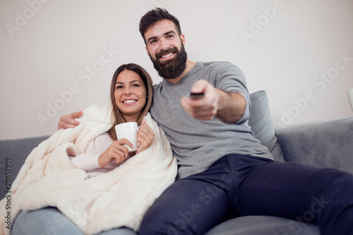 Happy young couple sitting and watching TV at home