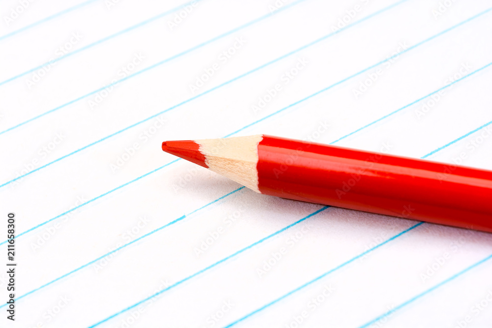 Red pencil close-up on a sheet of paper from a notepad. Stationery. Back to school. Lesson. Education. Painting. Red pencil close-up on a sheet of paper from a notepad. Stationery. Back to school. Lesson. Education. Painting.