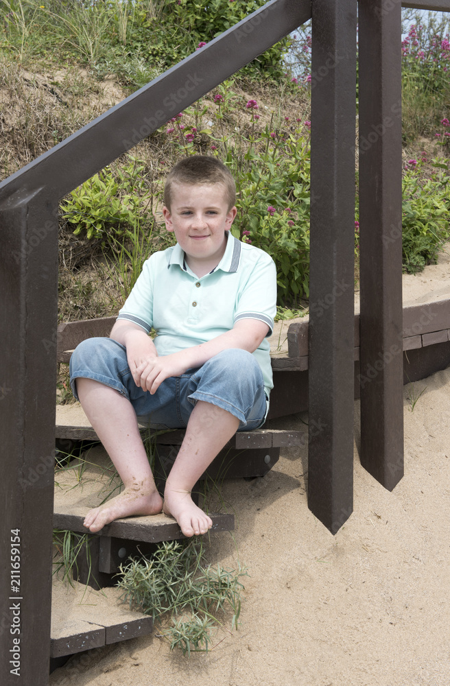Portrait of eleven year old boy sitting on steps on a beach on a sunny day Portrait of eleven year old boy sitting on steps on a beach on a sunny day