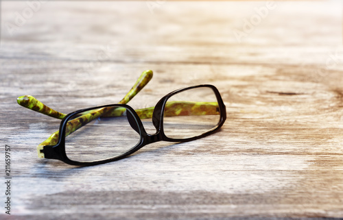Eyeglasses with green color placed on the wood table in the morning.