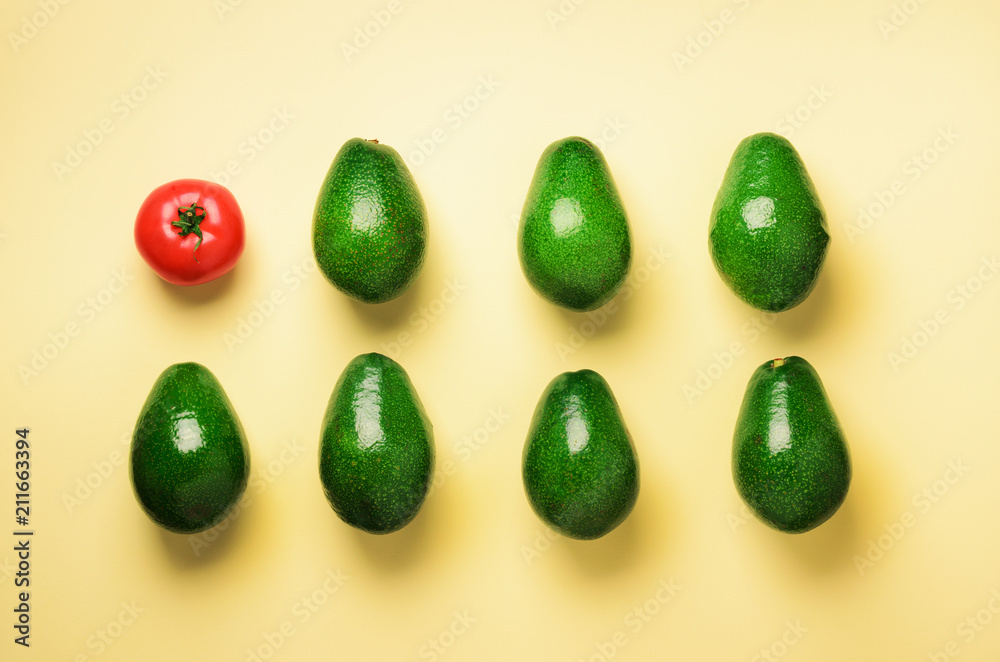 Green sliced avocado and red tomato on blue and yellow background. Top view. Pop art design, creative summer food concept. Minimal flat lay style. Green sliced avocado and red tomato on blue and yellow background. Top view. Pop art design, creative summer food concept. Minimal flat lay style.