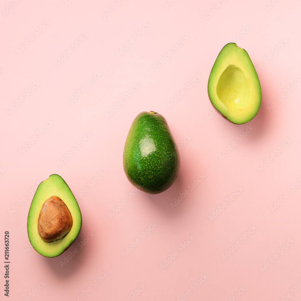 Organic avocado with seed, avocado halves and whole fruits on pink background. Top view. Square crop. Pop art design, creative summer food concept. Green avocadoes pattern in minimal flat lay style.