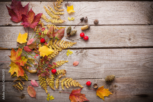 red berriaes and autumn leaves on old wooden background