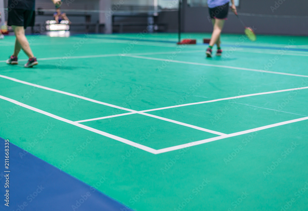 badminton court with blurred badminton player holding racket indoor court