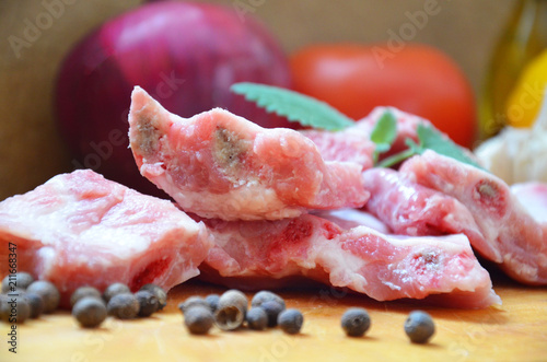 Raw uncooked pork ribs on a paper on dark brown wooden background. Ingredients for meat raw pork ribs sage, thyme, rosemary, pepper, basil, salt. photo