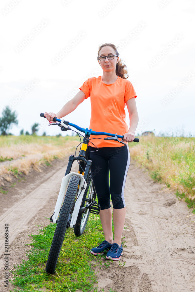 Woman is standing with a bicycle, a summer walk.