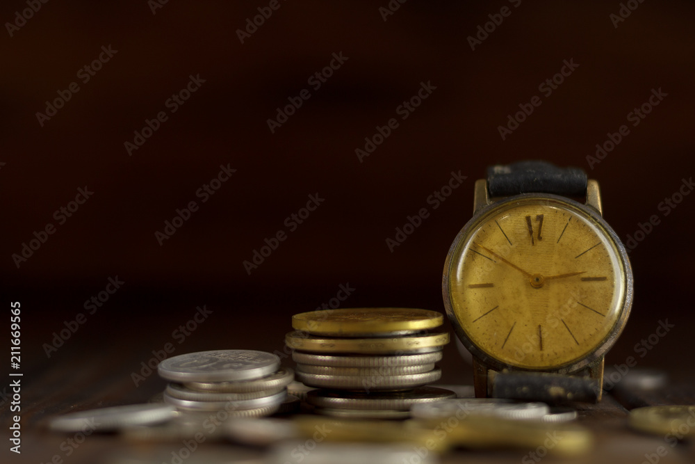 Time is money! Coins on each other and an old wristwatch. With dark background. Time is money! Coins on each other and an old wristwatch. With dark background.