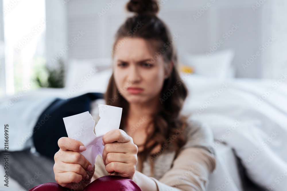 Photo with ex. Sad emotional young woman feeling cheerless and lonely while tearing photo with ex boyfriend Photo with ex. Sad emotional young woman feeling cheerless and lonely while tearing photo with ex boyfriend