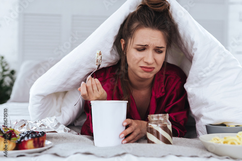 Ice cream. Stressed emotional woman eating big ice cream and crying after breakup with her handsome boyfriend