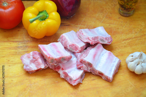 Raw uncooked pork ribs on a paper on dark brown wooden background. Ingredients for meat raw pork ribs sage, thyme, rosemary, pepper, basil, salt. photo