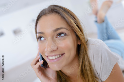 smiling woman using a smartphone while relaxing at home