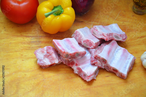 Raw uncooked pork ribs on a paper on dark brown wooden background. Ingredients for meat raw pork ribs sage, thyme, rosemary, pepper, basil, salt. photo