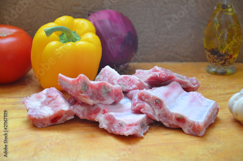 Raw uncooked pork ribs on a paper on dark brown wooden background. Ingredients for meat raw pork ribs sage, thyme, rosemary, pepper, basil, salt. photo