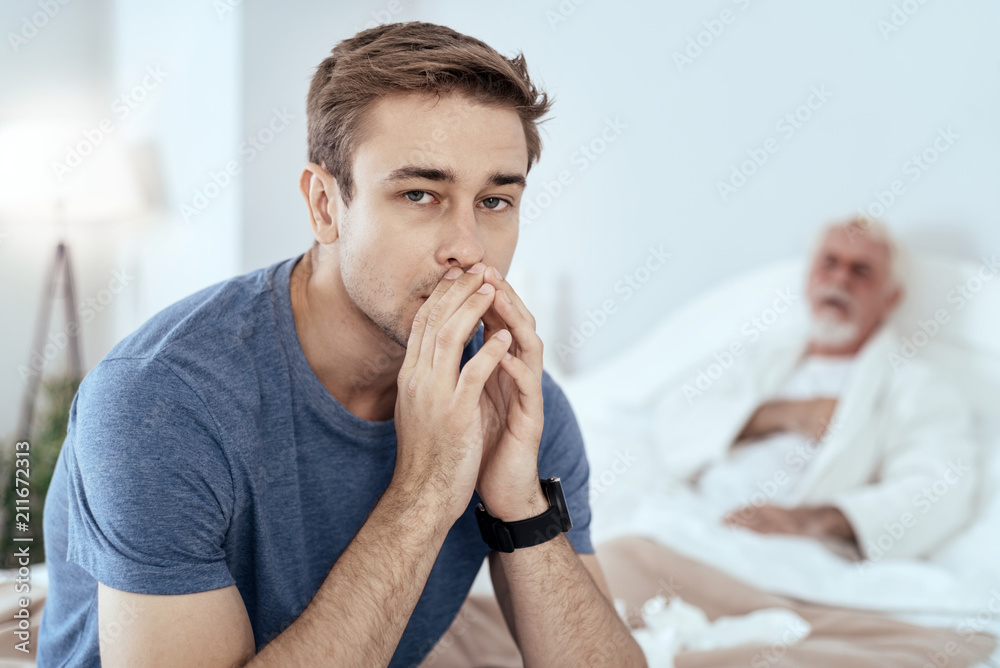 Sincere concern. Reflective man looking at camera and senior man posing on bed Sincere concern. Reflective man looking at camera and senior man posing on bed
