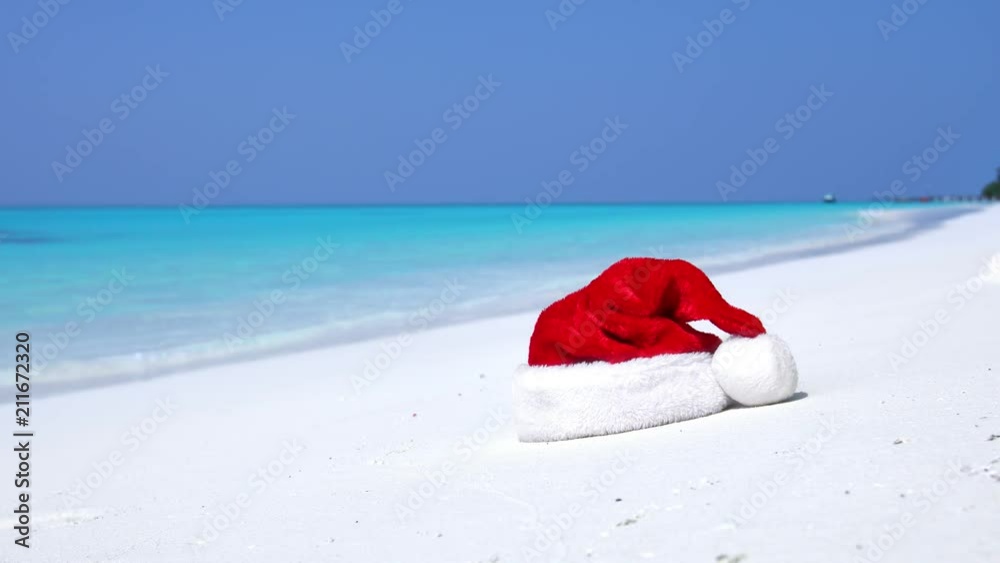 Christmas helper hat on tropical sandy beach with calm waves. Maldivian destination Christmas helper hat on tropical sandy beach with calm waves. Maldivian destination