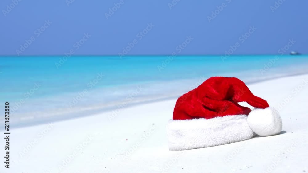 Christmas helper hat on tropical sandy beach with calm waves. Maldivian destination Christmas helper hat on tropical sandy beach with calm waves. Maldivian destination