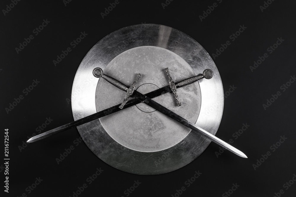 shiny metal shield and sword on a black isolated background shiny metal shield and sword on a black isolated background